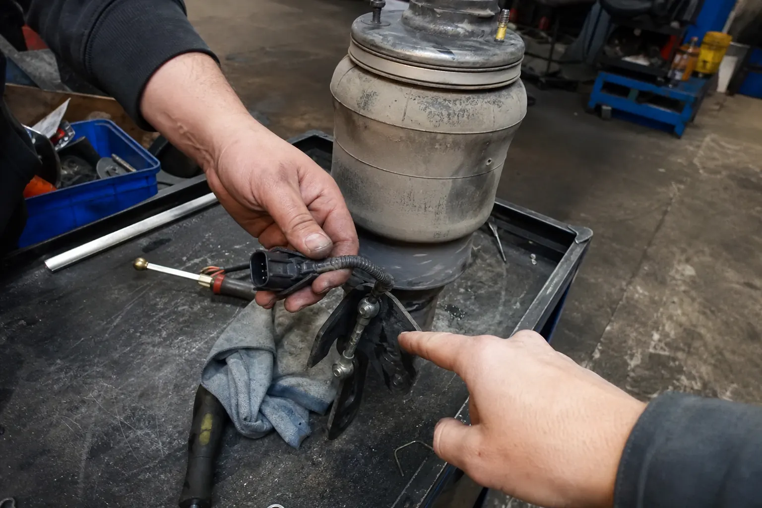 Ride height sensor connector and air spring being inspected on a worn workshop bench
